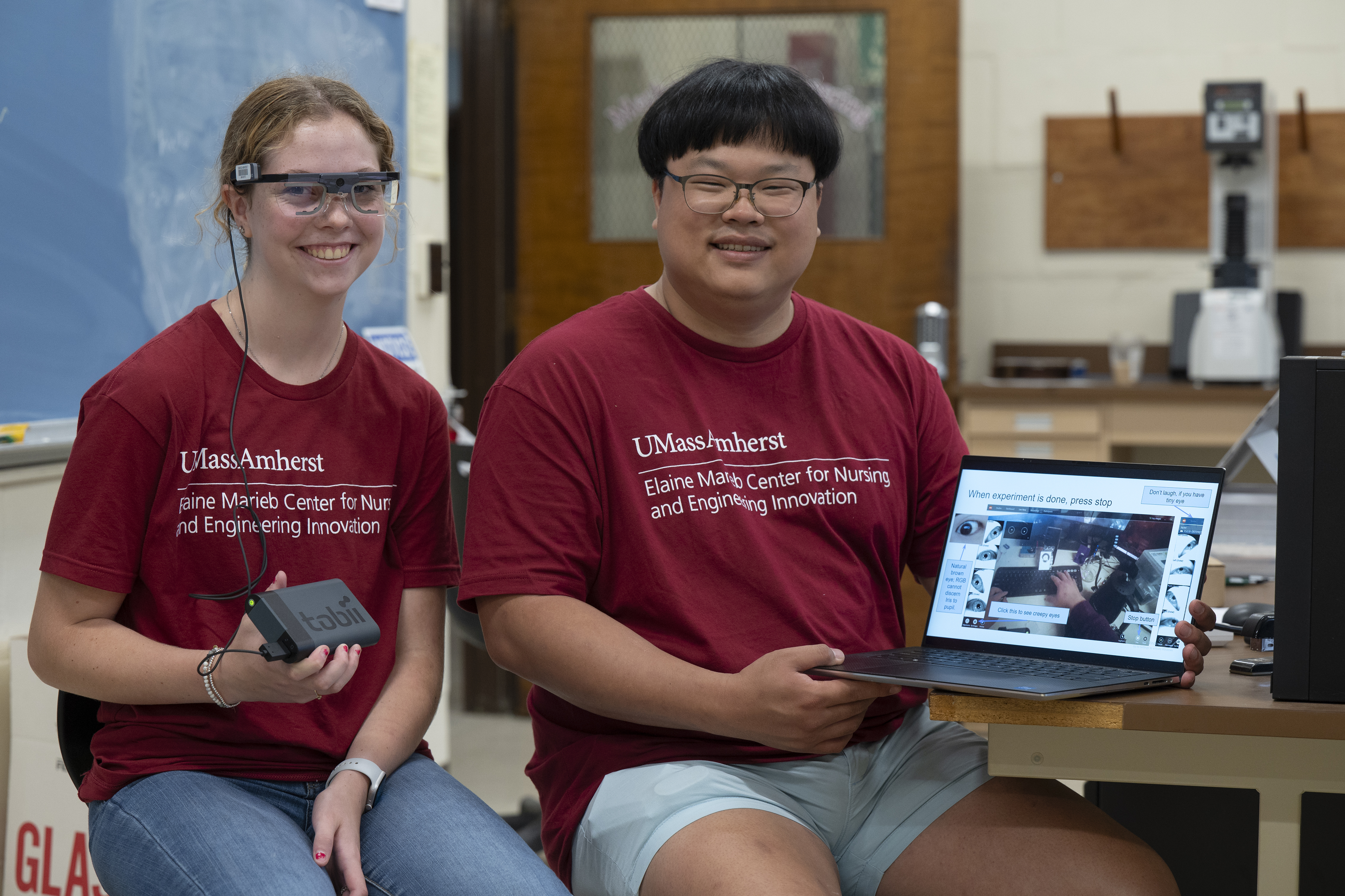 A student (left) wears eye-tracking glasses as doctoral student Seonhun Lee holds a laptop showing information about the study completed using the technology.